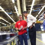 President Barack Obama examines a part held by Mike Clements during a tour of Allison Transmission in Indianapolis, Indiana, May 6, 2011. Plant manager Mike Clements stands at right. (Official White House Photo by Samantha Appleton)
